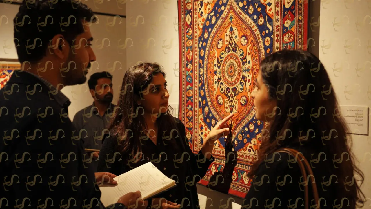 A couple examines a textile artwork from Lahore, guided silently by an expert in the emerging artists section.